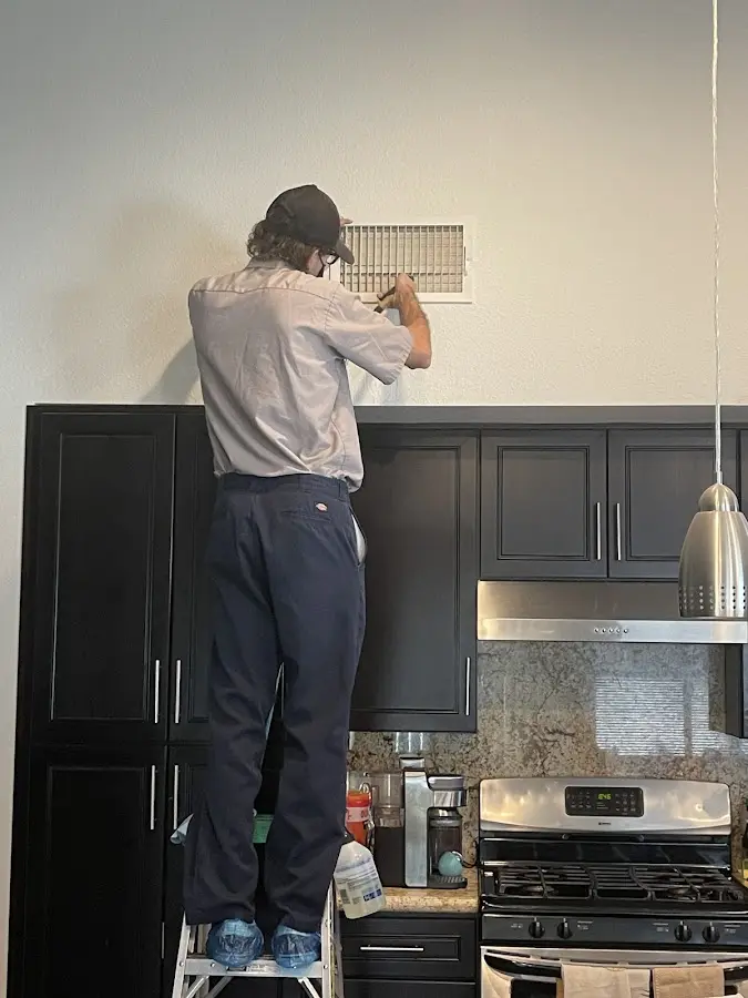 Technician inspecting an air vent during HVAC service in Lewisville